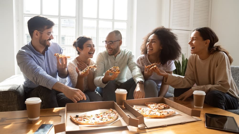 Buddies eating ordered pizza for home party